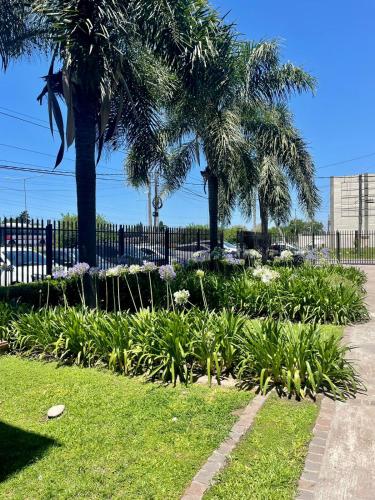 a garden with palm trees and plants in front of a fence at Punto Maschwitz Alquileres - Departamento dos ambientes in Ingeniero Maschwitz