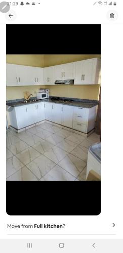 a kitchen with white cabinets and a tile floor at July in San Felipe de Puerto Plata