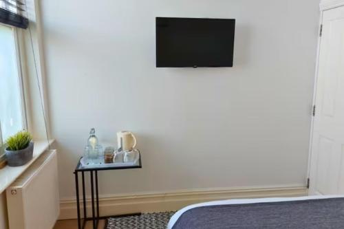 a room with a bed and a television on a wall at Stylish Double Room in City Centre - Shared Bathroom - Parking in Preston