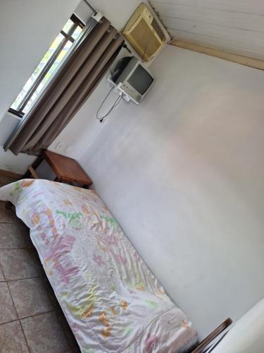 a small bedroom with a bed and a tv at Pousada Hotel Araguaia in Aragarças