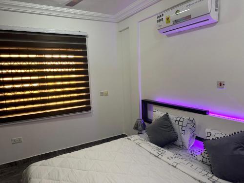 een slaapkamer met een bed en een raam met paarse verlichting bij KANS KRIB in Accra