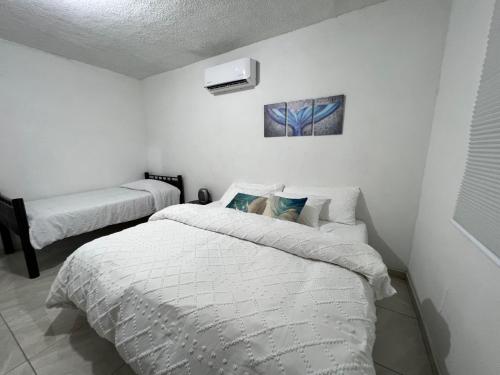 two beds in a room with white walls at Puerto San Carlos Bay House & Tours -1st Floor- in San Carlos