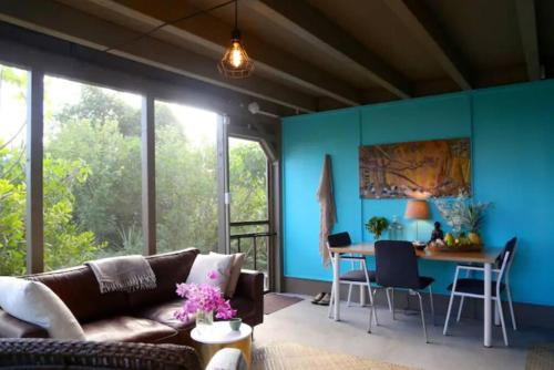 een woonkamer met een bruine bank en blauwe muren bij Eco-Farm Glamping Mini House in Pahoa