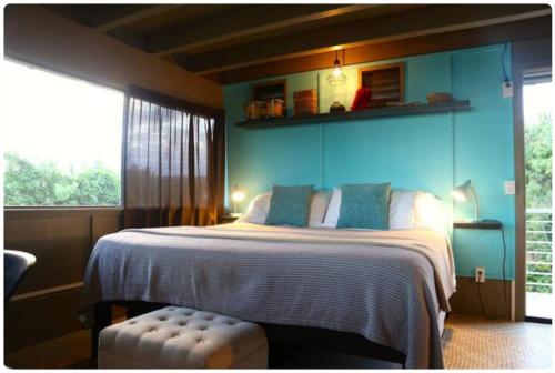 een slaapkamer met een groot bed met een blauwe muur bij Eco-Farm Glamping Mini House in Pahoa
