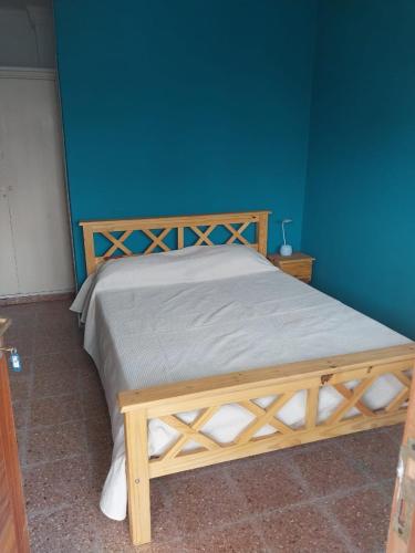 uma cama de madeira num quarto com uma parede azul em La Huella em Colonia Chapadmalal
