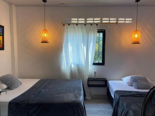 a bedroom with two beds and two lights and a window at Cabaña Aldea Santorini in Doradal