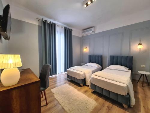 Habitación de hotel con 2 camas y mesa en Villa Mishel Suites en Berat