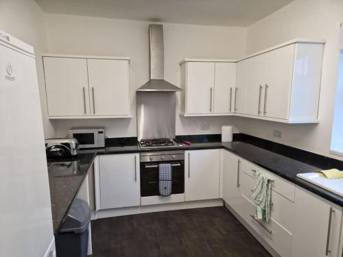 a kitchen with white cabinets and a stove top oven at Oasis Abode @Shiremoor 