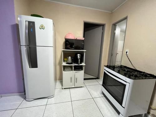 Il comprend une cuisine équipée d'un réfrigérateur blanc et d'une cuisinière. dans l'établissement Sítio em Marimbondo, à Marimbondo