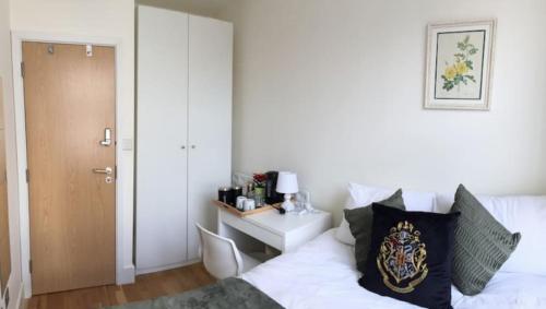um quarto com uma cama branca e uma secretária com uma mesa de cabeceira em Comfort Bedrooms near Euston - 161/2 em Londres