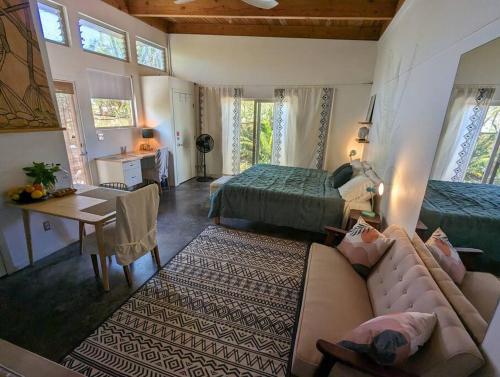 a bedroom with a couch and a bed and a desk at Eco-Farm Self-Contained Studio in Pahoa