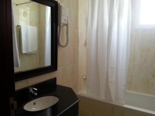 uma casa de banho com um lavatório e um chuveiro com um espelho. em Muscat International Hotel Plaza em Salalah