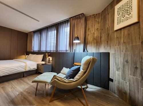 a bedroom with a bed and a chair in a room at 花蓮品悅文旅Hualien Pink Corner Hotel in Hualien City