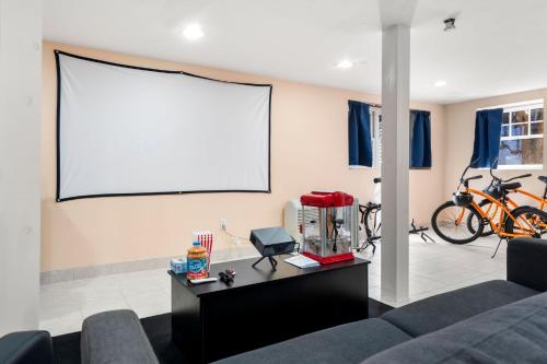 sala de estar con sofá y pantalla de proyección en Hot Tub, Electric Bikes, Solo Stove, Projector, Smores, en Marblehead
