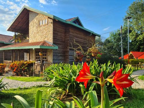 una casa de madera con una flor roja delante de ella en Cabañas Filadelfia, en Santa Rosa de Cabal