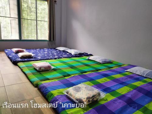 2 Betten nebeneinander in einem Zimmer in der Unterkunft เรือนแรก โฮมสเตย์ in Ban Tha Sao