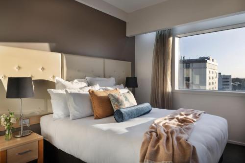 a bedroom with a large bed with a large window at Fable Christchurch in Christchurch