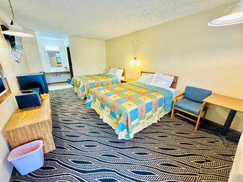 Habitación de hotel con 2 camas y escritorio en Holiday Pines Inn and Suites en Jay