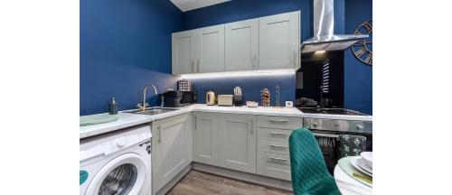 a kitchen with blue walls and a washer and dryer at Cozy 3 Bedroom Flat in London! in London