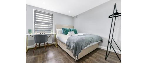 a bedroom with a bed and a desk and a window at Cozy 3 Bedroom Flat in London! in London