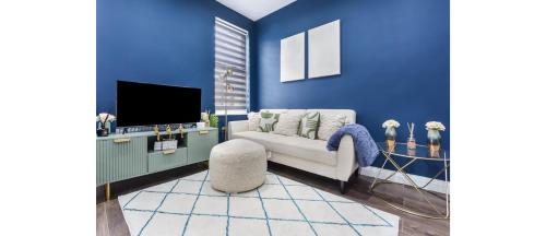 a blue living room with a couch and a tv at Cozy 3 Bedroom Flat in London! in London