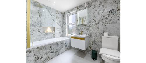 a bathroom with a white toilet and a sink at Cozy 3 Bedroom Flat in London! in London