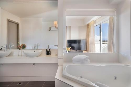 a white bathroom with two sinks and a tub at Fable Christchurch in Christchurch