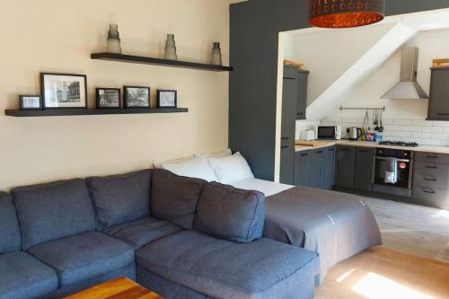 a living room with a blue couch and a kitchen at Large Studio Room in City Centre (Shared Bathroom) in Preston