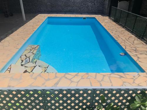 a blue swimming pool with a stone pathway around it at Chez Rereani in Punaauia
