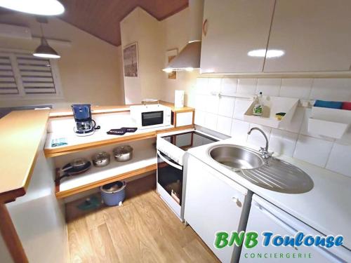 une petite cuisine avec un évier et une cuisinière dans l'établissement ► BNB TOULOUSE ► Le Charmant Balmanais • Clim • Garage • 24/7, à Balma