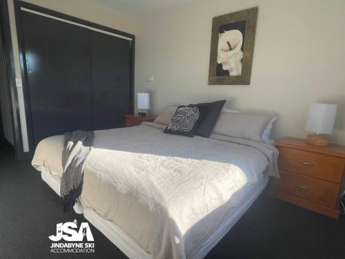 a bedroom with a bed and a picture on the wall at Pine Peak in Jindabyne
