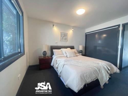 a bedroom with a large bed and a large window at Pine Peak in Jindabyne
