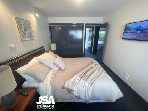 a bedroom with a bed with white sheets and pillows at Pine Peak in Jindabyne
