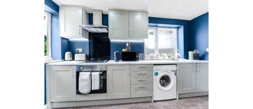 a white kitchen with a washing machine and a washer at Sleek Modern 3BR Flat in Nunhead in London