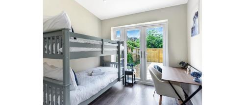a room with a bunk bed and a desk and a desk at Sleek Modern 3BR Flat in Nunhead in London