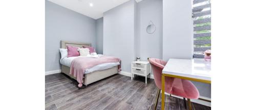 a small bedroom with a pink bed and a desk at Sleek Modern 3BR Flat in Nunhead in London
