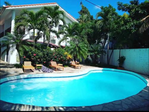 a swimming pool in front of a house with palm trees at Hotel Plama Cana in Sosúa
