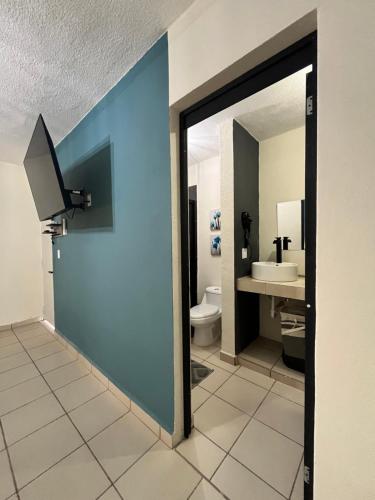 a bathroom with a toilet and a blue wall at Departamentos Yahelik in Cabo San Lucas