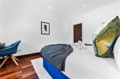 ein Schlafzimmer mit einem Bett und einem blauen Stuhl in der Unterkunft Enchanted Oasis: A Cozy Flat w/ Botanical Charm in Hanwell