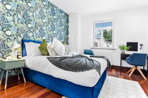 ein Schlafzimmer mit einem blauen und weißen Bett mit einer Wand in der Unterkunft Enchanted Oasis: A Cozy Flat w/ Botanical Charm in Hanwell