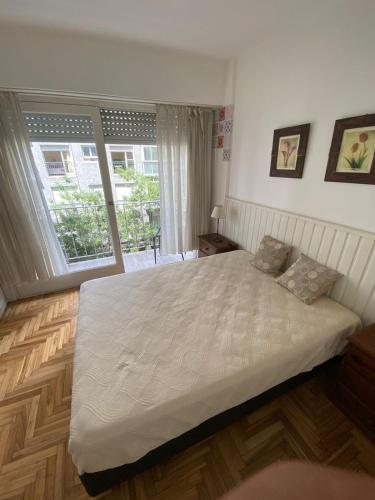 a bedroom with a large white bed and a window at Depto 2 ambientes Zona Aldrey in Mar del Plata