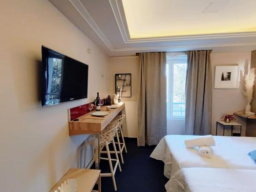 a room with a bed and a desk and a television at GREEN Studio climatisé, vue sur golf proche Montpellier in Montpellier