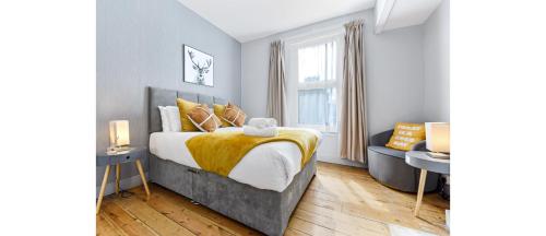 een slaapkamer met een bed en een bank bij City Escape: Sleek and Comfy 3 BR House w/ Garden in Hither Green