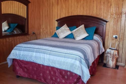 1 dormitorio con 1 cama con almohadas azules y blancas en Cabaña, en Pirque