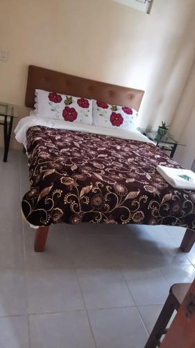 - un lit avec un couvre-lit brun et des fleurs rouges dans l'établissement Departamento con área verde, à Zacatlán