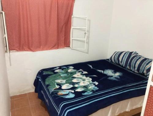 een bed met een blauwe deken met bloemen erop bij Sueño de bugambilia in Oaxaca City
