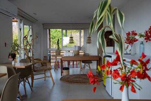 una sala da pranzo con tavoli, sedie e fiori rossi di Pousada Mar em Mim a Fernando de Noronha