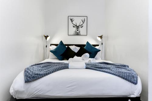 1 dormitorio con 1 cama grande con almohadas azules en Vibrant 1 BD Retreat - Perfect for Couples, en Hanwell
