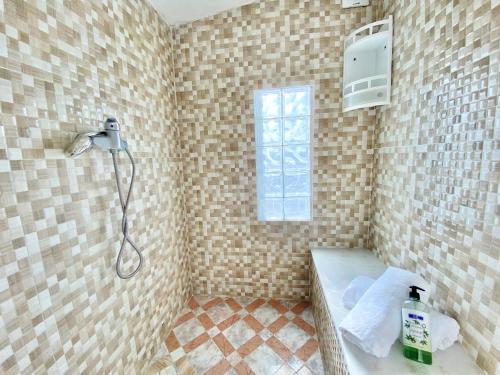 a bathroom with a shower with a sink and a window at oualidia surfhouse in Oualidia
