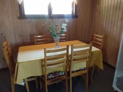 a dining room table with a vase of flowers on it at Cabañas Vista al Lago in Ensenada